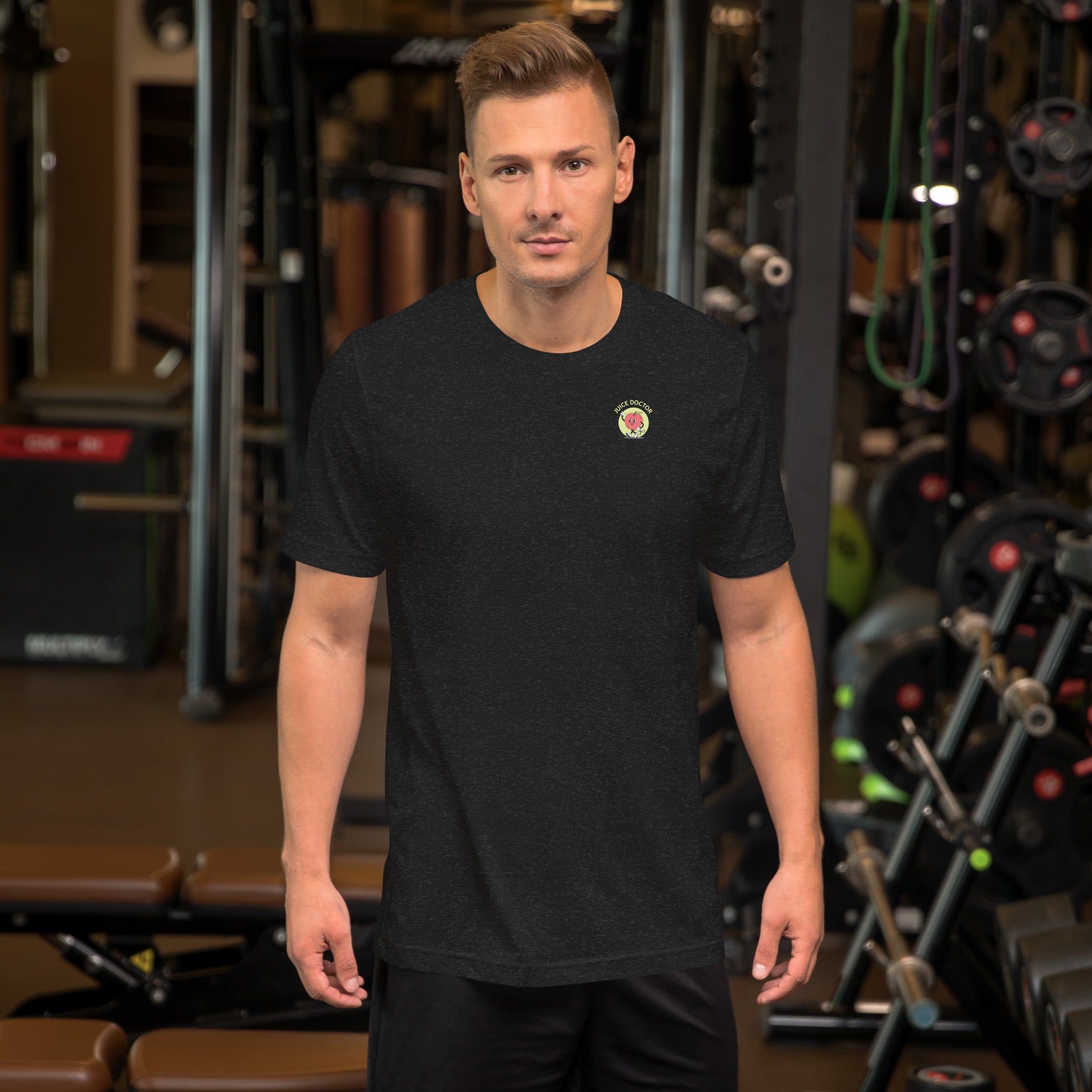 Model wearing black heather Juice Doctor unisex t-shirt with embroidered logo, standing in a gym setting. Ideal for active lifestyles and casual wear.
